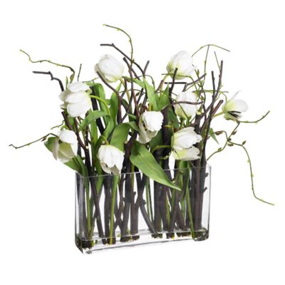 White tulips with twigs in glass vase